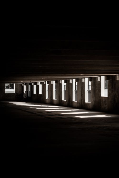 Free Dramatic light and shadow patterns in an empty hallway create a moody atmosphere. Stock Photo