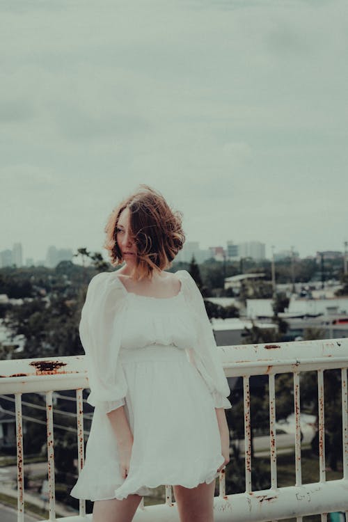 A Woman in White Long Sleeve Dress Standing on the Rooftop