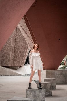 Woman posing confidently on concrete under angular modern architecture.