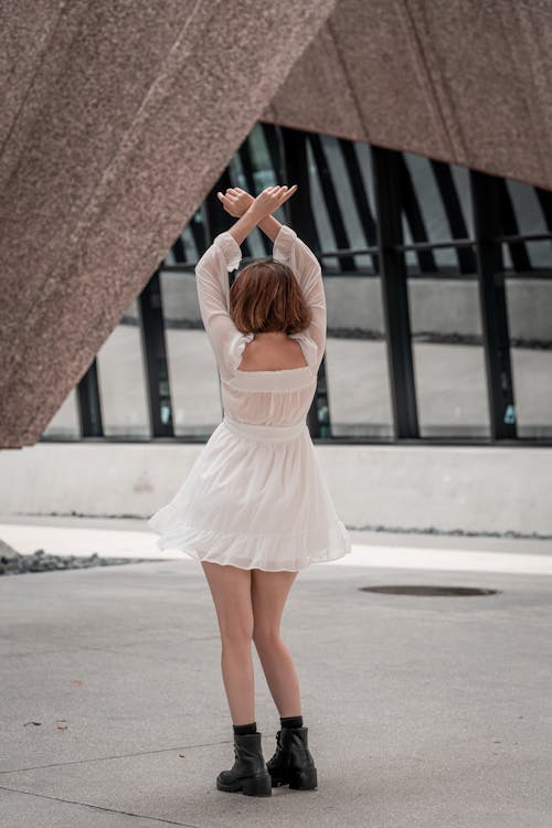 A Woman in White Dress Raising Her Arms