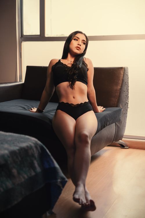 Free A young woman in black lingerie lounging indoors, exuding elegance and style. Stock Photo