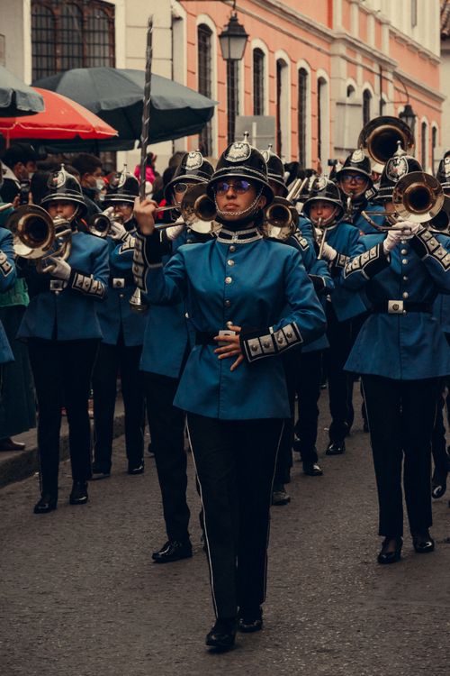Free A vibrant marching band performs in a city parade, showcasing blue uniforms and musical instruments. Stock Photo