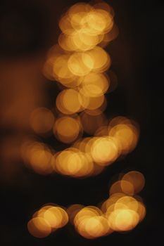 Defocused warm golden bokeh circles with a dark background, creating an abstract and dreamy effect.