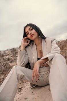Striking portrait of a woman in a beige suit exuding elegance in a desert landscape.