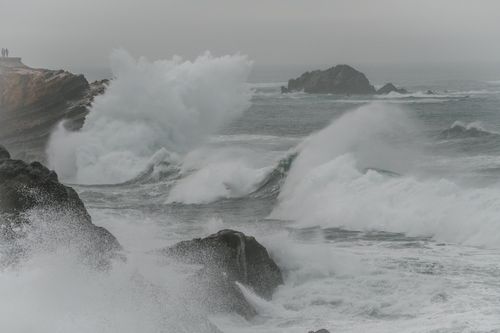 Free Powerful waves crashing against rocky cliffs on a misty day with a dramatic seascape. Stock Photo