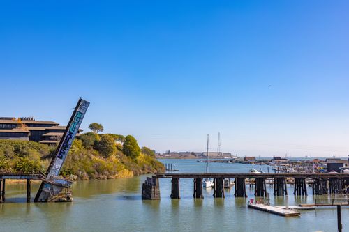 Free A tranquil harbor view featuring an abandoned graffiti bridge against clear blue skies. Stock Photo