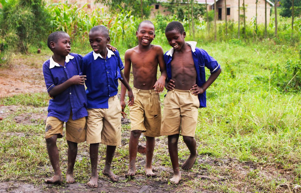 Four smiling boys in school uniforms in rural Uganda