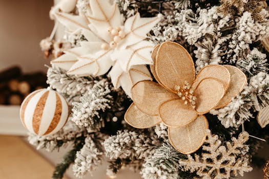 Close-up of festive gold and white ornaments on a snowy Christmas tree branch, creating a warm holiday ambiance.