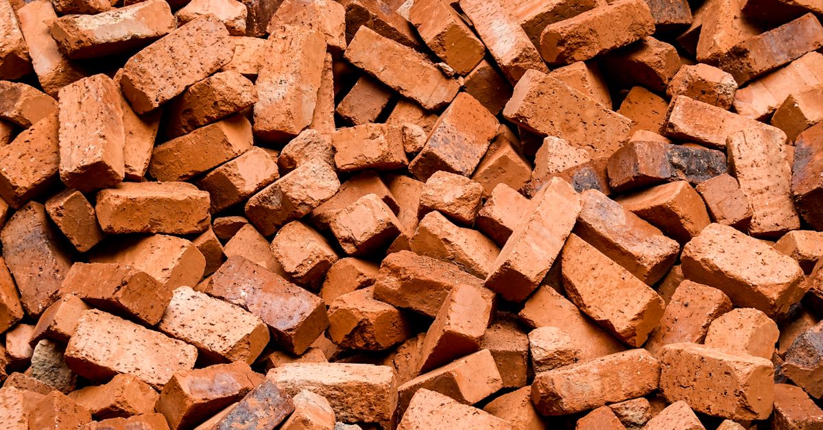 High-quality close-up image of a large pile of red clay bricks, ideal for construction projects.