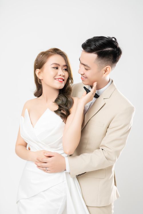 Free A classy wedding couple in a cozy embrace with a white backdrop. Stock Photo
