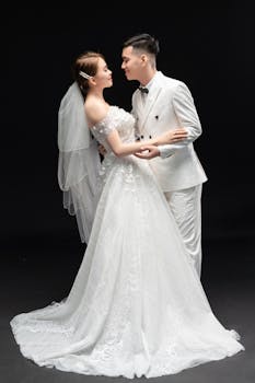 A loving wedding couple in elegant attire embracing tenderly against a black background.