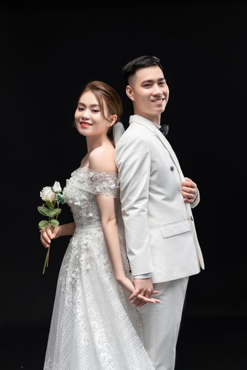Free A bride and groom in elegant attire, posing back to back in a studio. Stock Photo