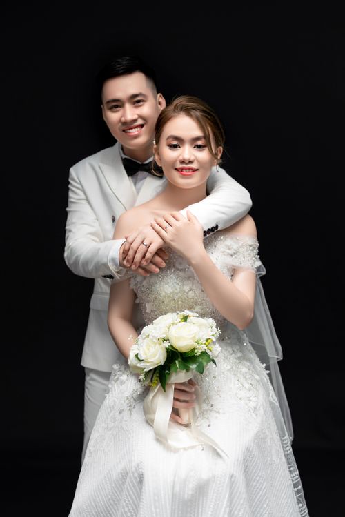 Free Studio wedding photoshoot of a happy newlywed couple embracing, showcasing elegant attire. Stock Photo