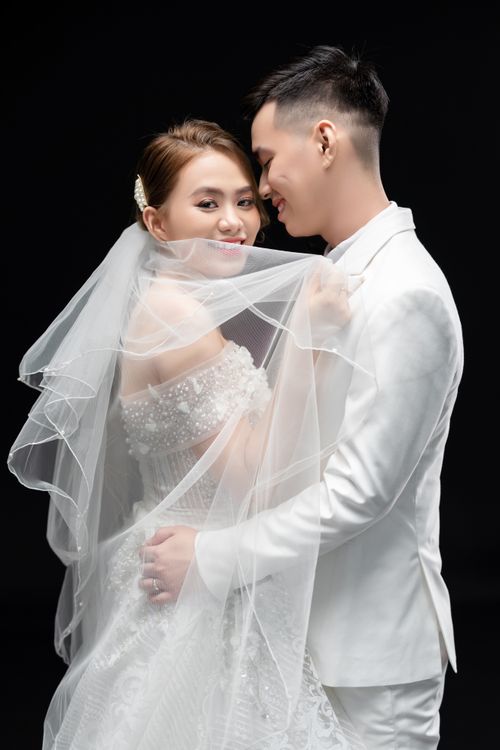 Free Beautiful Asian couple in wedding attire embracing in a studio photoshoot. Stock Photo