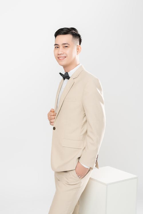 Man Wearing a Beige Suit Posing with Hand on Chest
