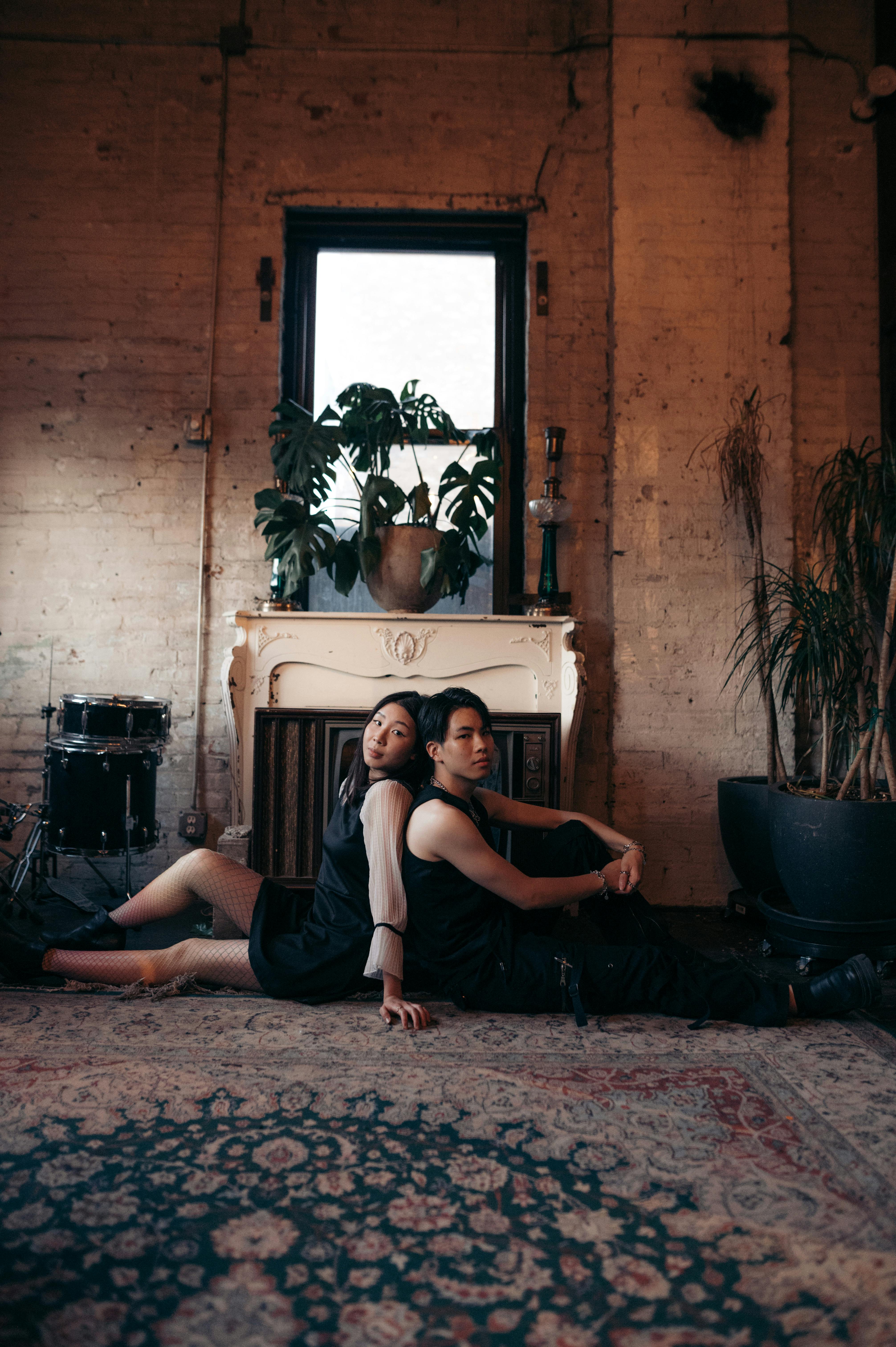 woman and man sitting back to back on a rug