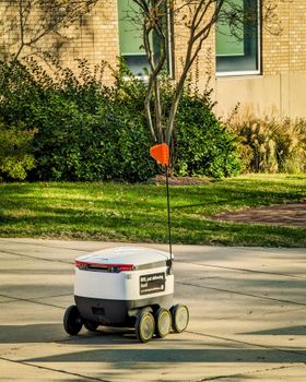 A sleek autonomous delivery robot navigates a sunny urban sidewalk, enhancing modern transportation.