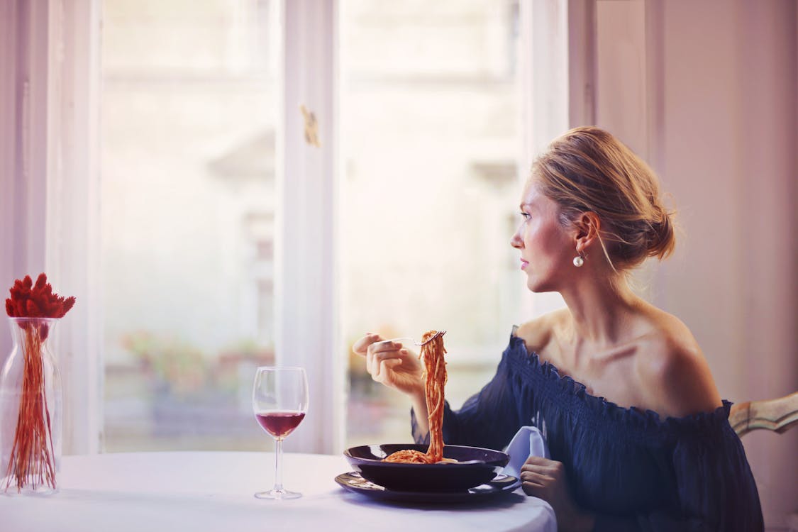 Free Woman Sitting on Chair While Eating Pasta Dish Stock Photo