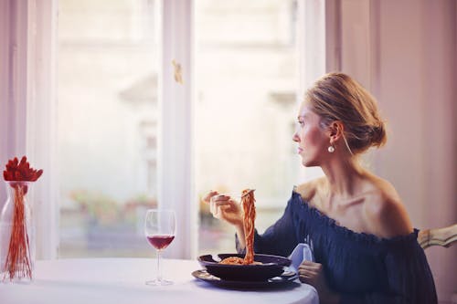 Free Woman Sitting on Chair While Eating Pasta Dish Stock Photo