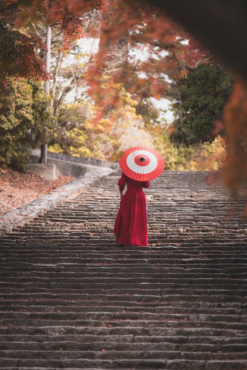 A Woman in a Red Dress Going Up Concrete Stairs
