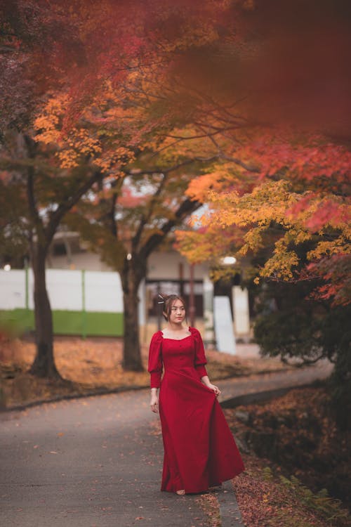 Woman in Red Dress Walking on Road