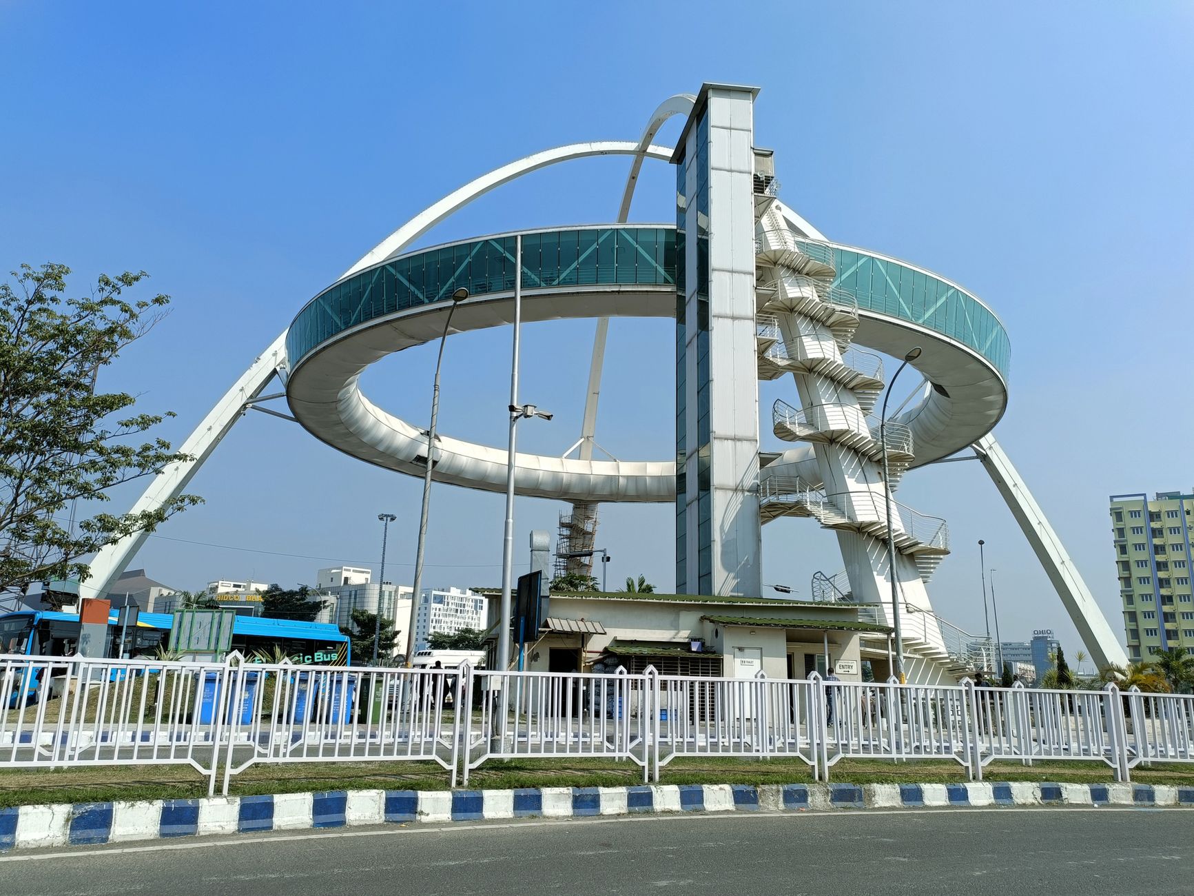 Low angle view of a modern skywalk in urban India under a clear blue sky.