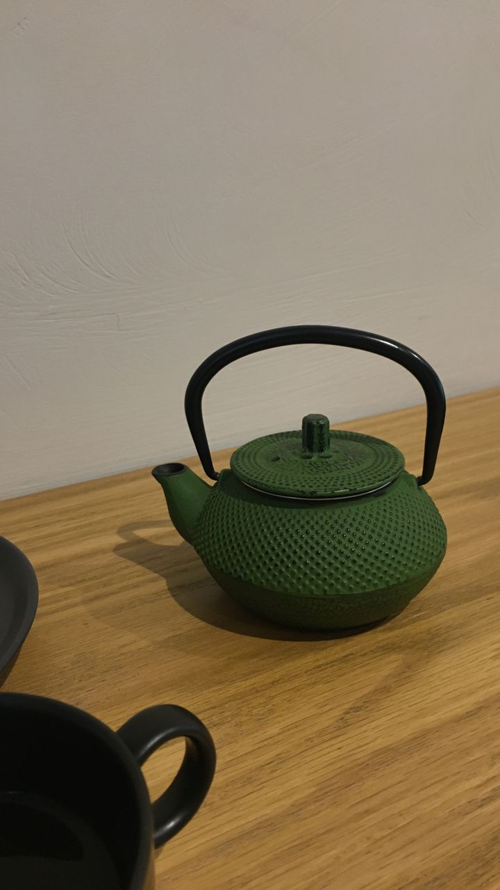 black pre-seasoned cast iron kettle with a wooden handle sitting on a coffee bar counter