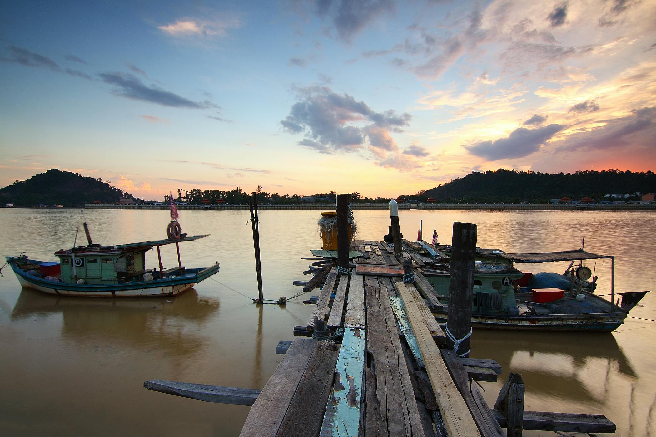 日落时分，宁静的湖面上映现出木码头和渔船的景象