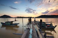 日落时分，宁静的湖面上映现出木码头和渔船的景象