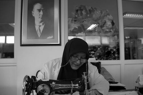 A Grayscale Photo of a Woman Wearing Headscarf and Eyeglasses