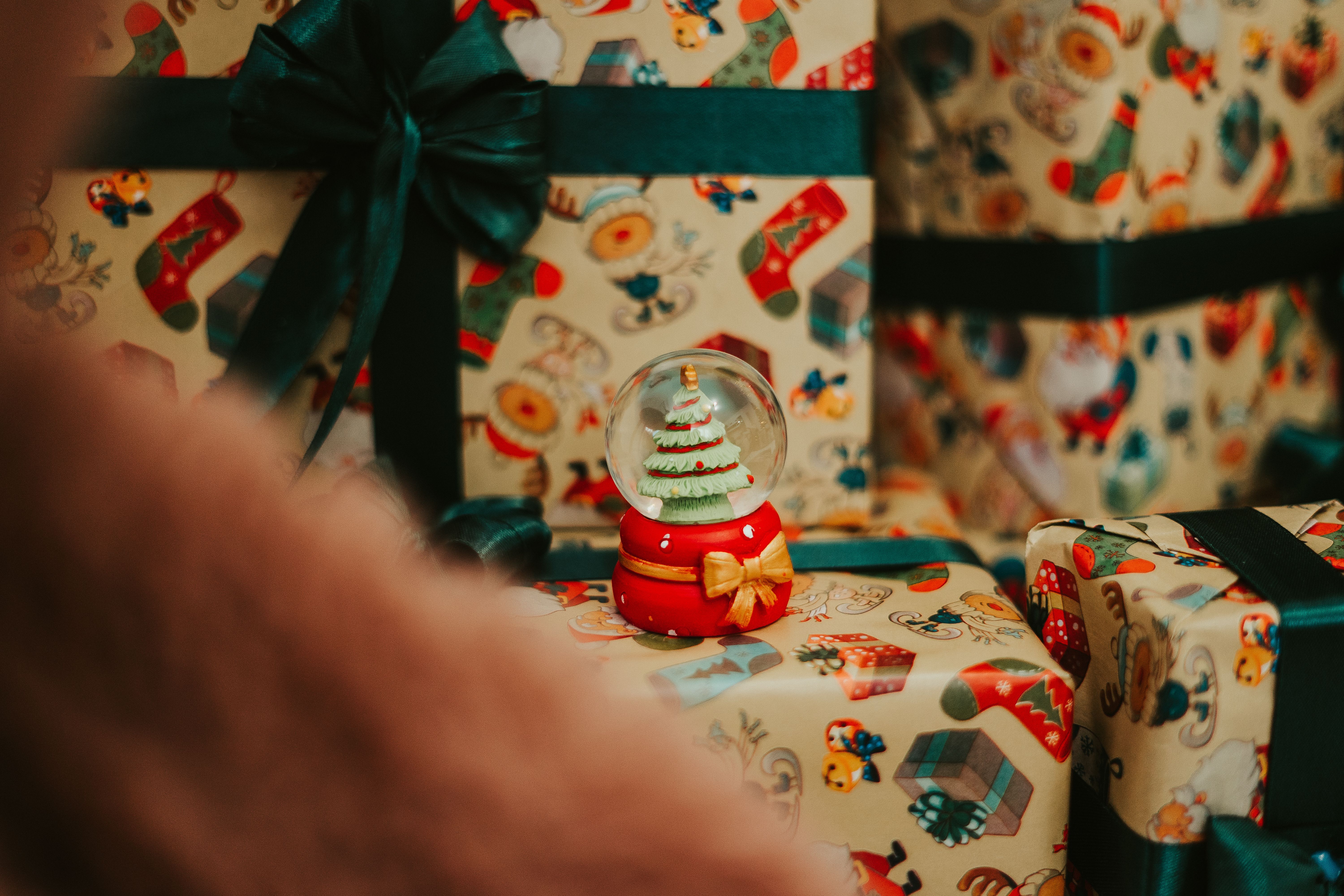 Colorful Christmas gifts with a snow globe and holiday decorations, evoking festive cheer.