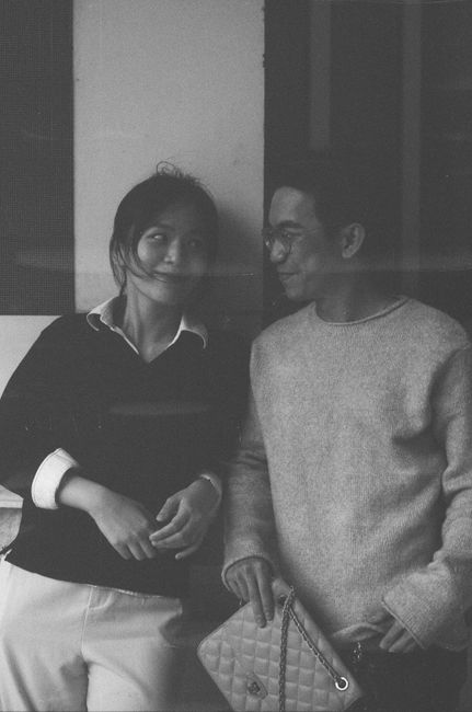 A candid black and white portrait of a smiling couple standing together indoors.
