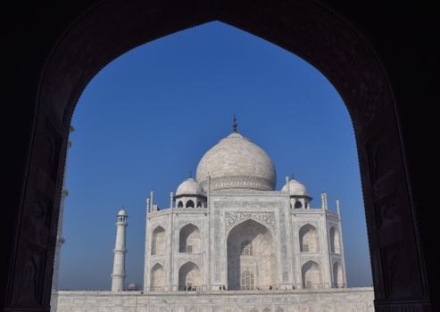 Stunning image of the Taj Mahal framed by an arch, showcasing its architectural beauty against a vibrant blue sky., free online jigsaw puzzle on JigsawPuzzlesFreeOnline.org