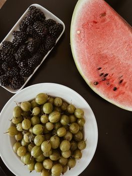 A vibrant arrangement of blackberries, gooseberries, and watermelon on a dark background.