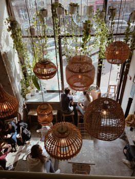 A cozy cafe interior featuring rattan pendant lamps and lush greenery for an inviting atmosphere.