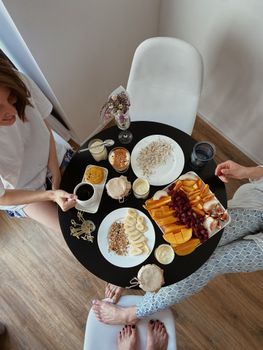 Overhead view of friends enjoying a colorful breakfast with fruit and yogurt.