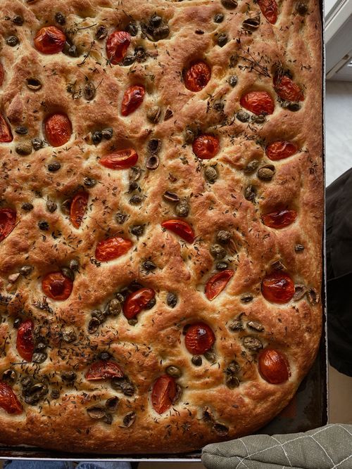 Free Italian focaccia with olives and cherry tomatoes, perfect for a savory meal. Stock Photo
