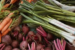 A variety of fresh vegetables including carrots, beetroots, and leeks on a market stall.