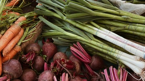 A variety of fresh vegetables including carrots, beetroots, and leeks on a market stall.