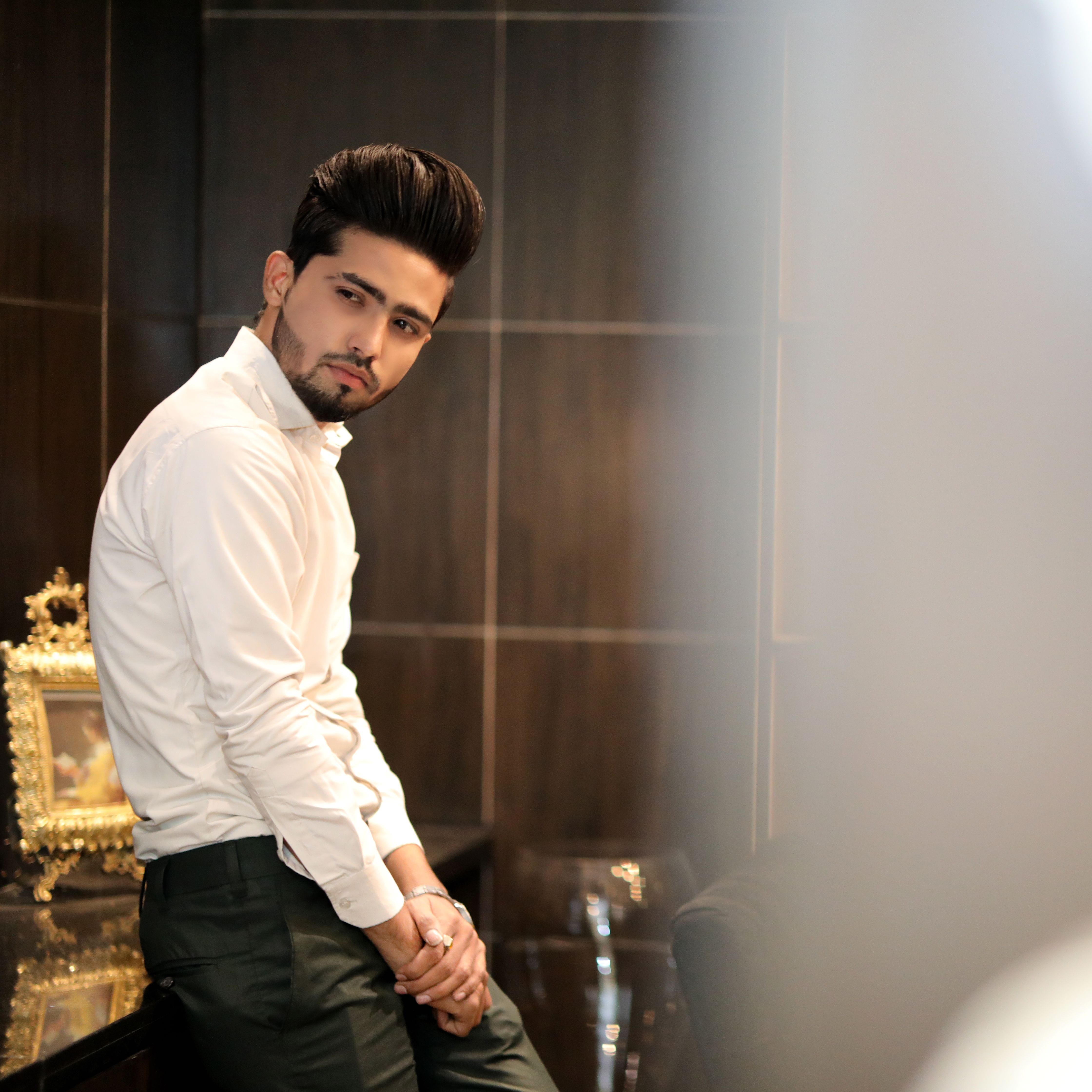 Fashionable man with short hair posing indoors in refined attire, exuding confidence.