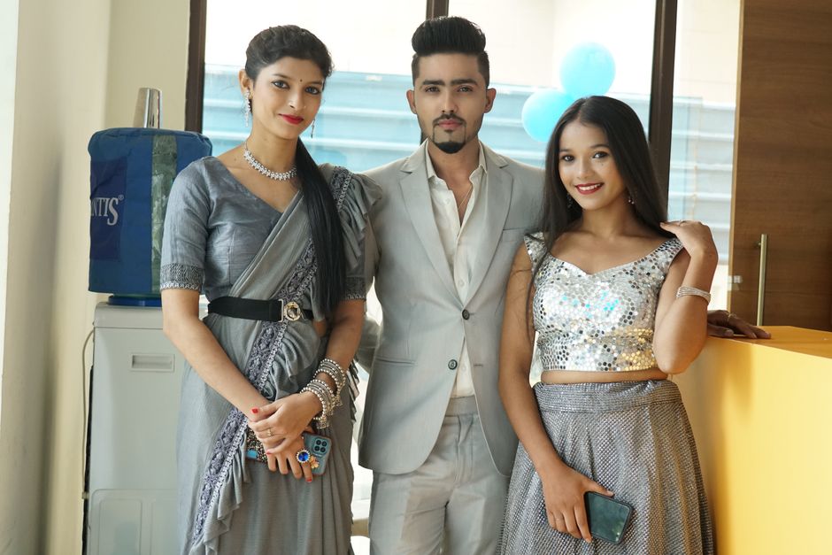 Group portrait of stylish young adults in traditional attire, smiling indoors.