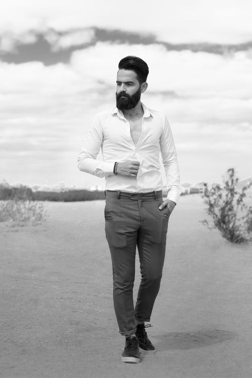 Free A fashionable man strolls through a desert landscape with a confident pose. Stock Photo
