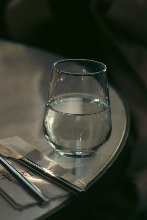 Free A close-up shot of a glass of water on a restaurant table, with cutlery and napkins. Stock Photo