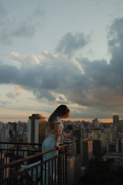 Woman on a Terrace Leaning against a Balustrade and Looking at Cityscape