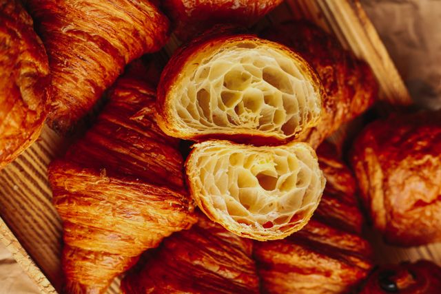 Halved croissant showing a honeycomb crumb resting on a pile of flaky croissants