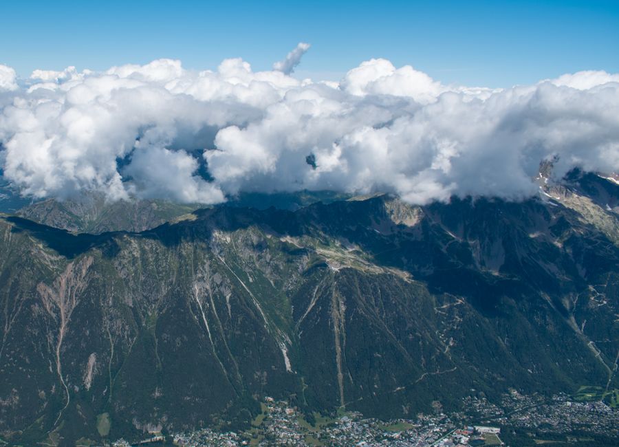 Breathtaking aerial view of Chamonix Valley and mountains under a vibrant blue sky with clouds.