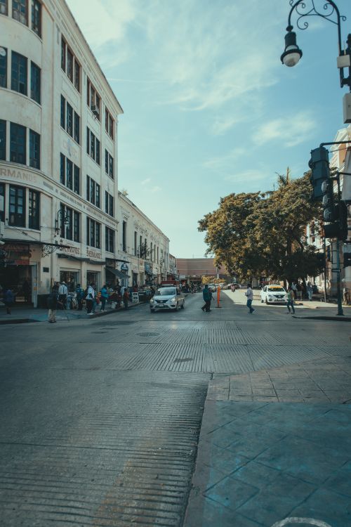 Free Lively city street with people, cars, and tall buildings under a clear blue sky. Stock Photo
