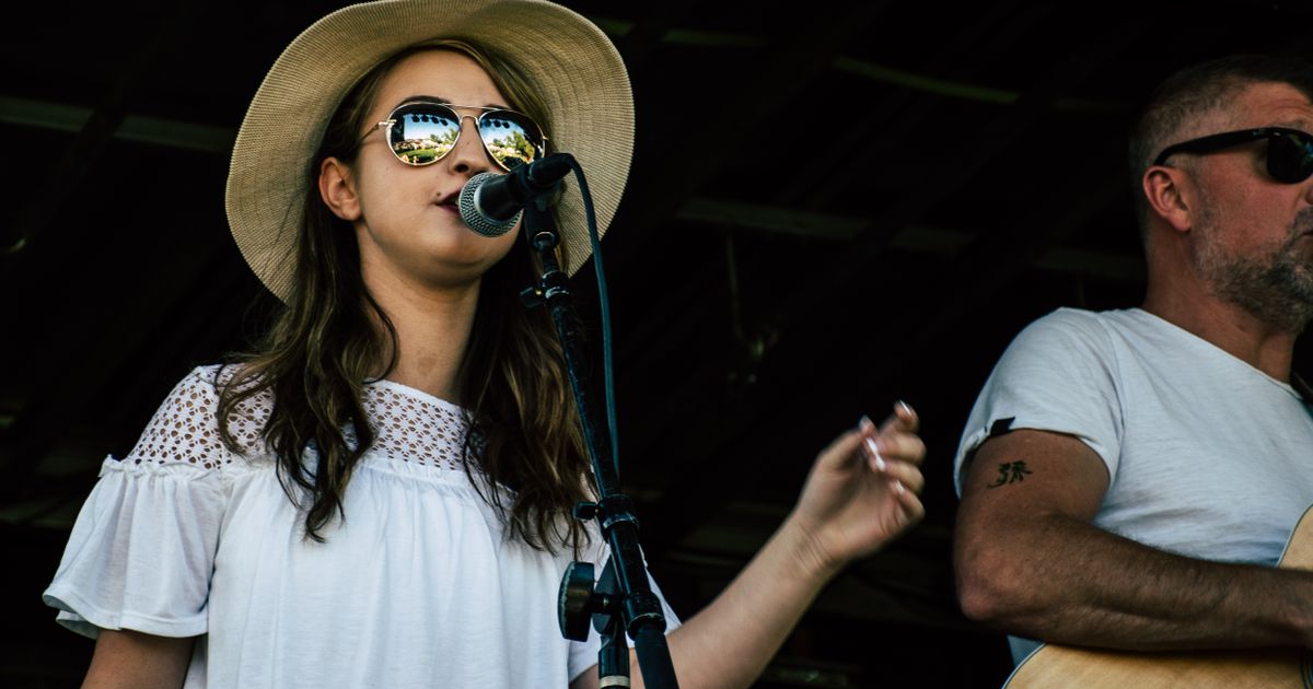A vibrant outdoor concert featuring a female singer and male guitarist performing passionately on stage.