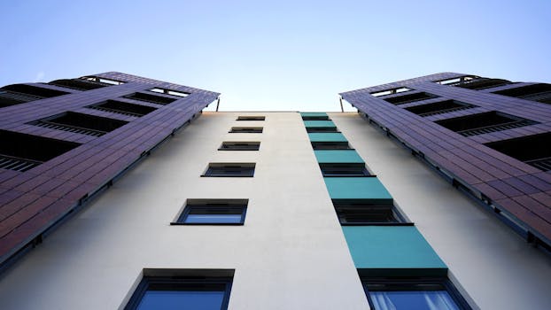 从低角度仰望现代摩天大楼，玻璃立面映衬着晴朗的天空