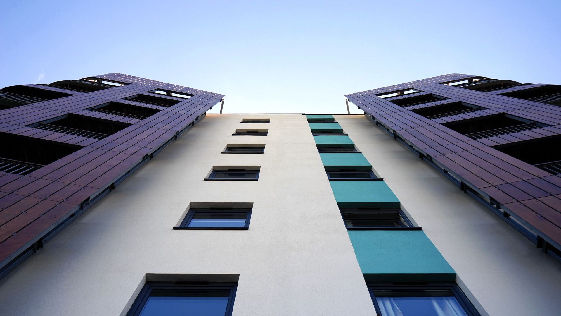 Low angle view of a modern skyscraper with glass facade against a clear sky.